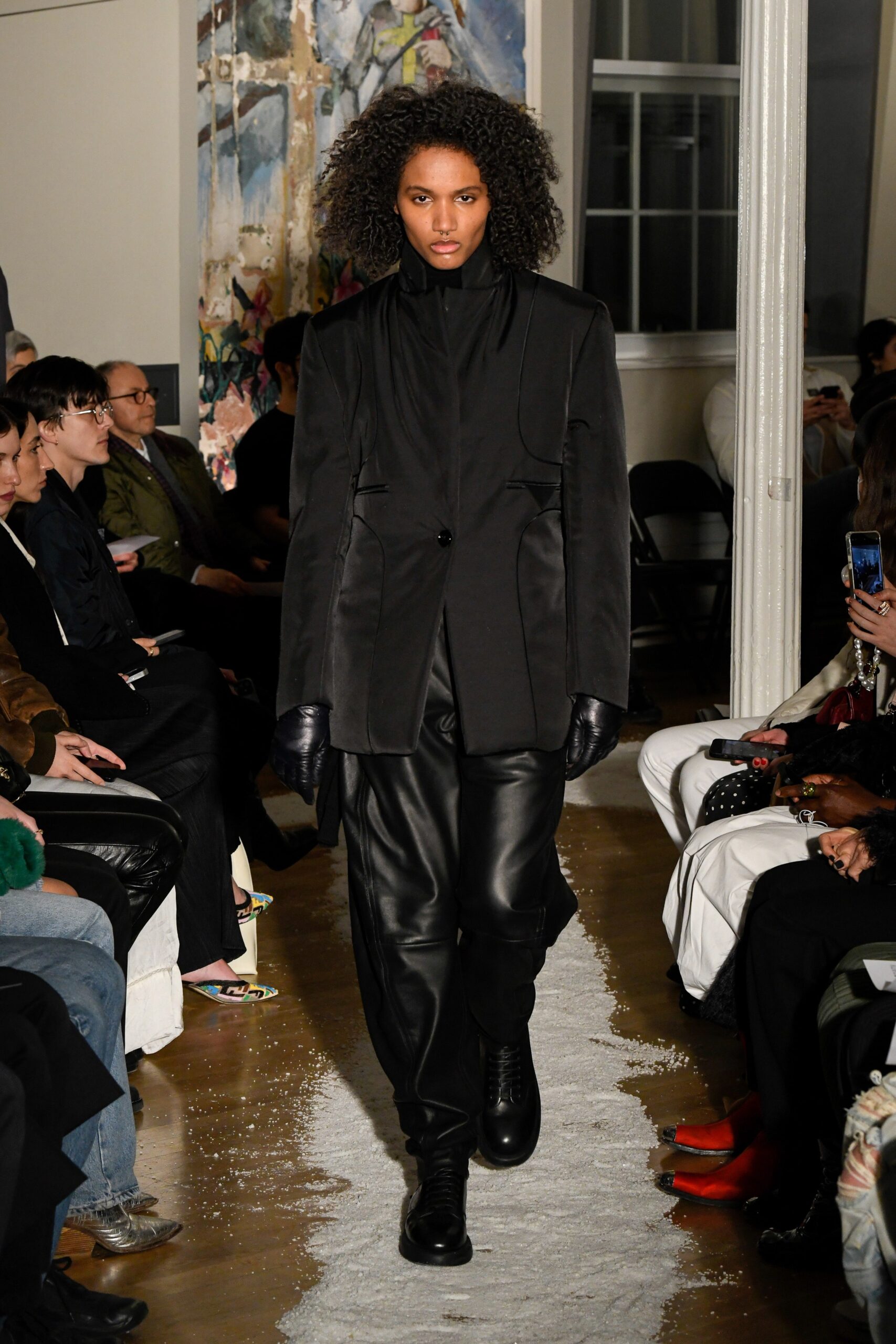 A fitted black leather jacket with long sleeves and structured pants, showcasing a modern silhouette.