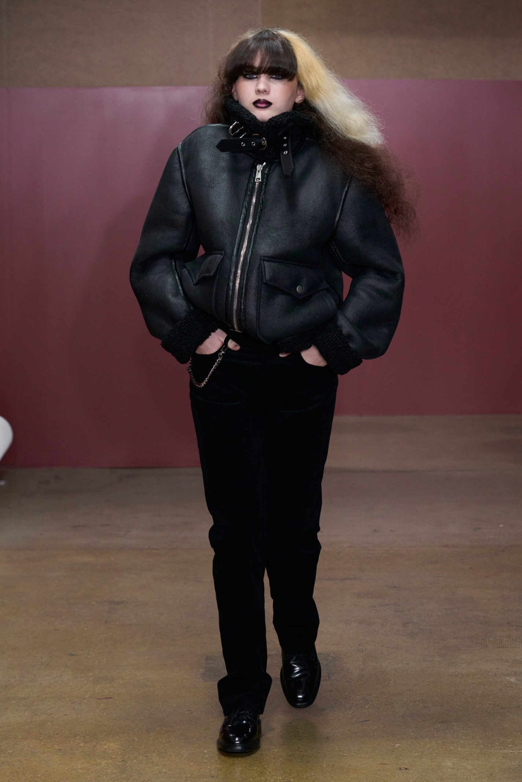 A fitted black leather jacket with a collared neck and zippered detail, paired with matching pants.