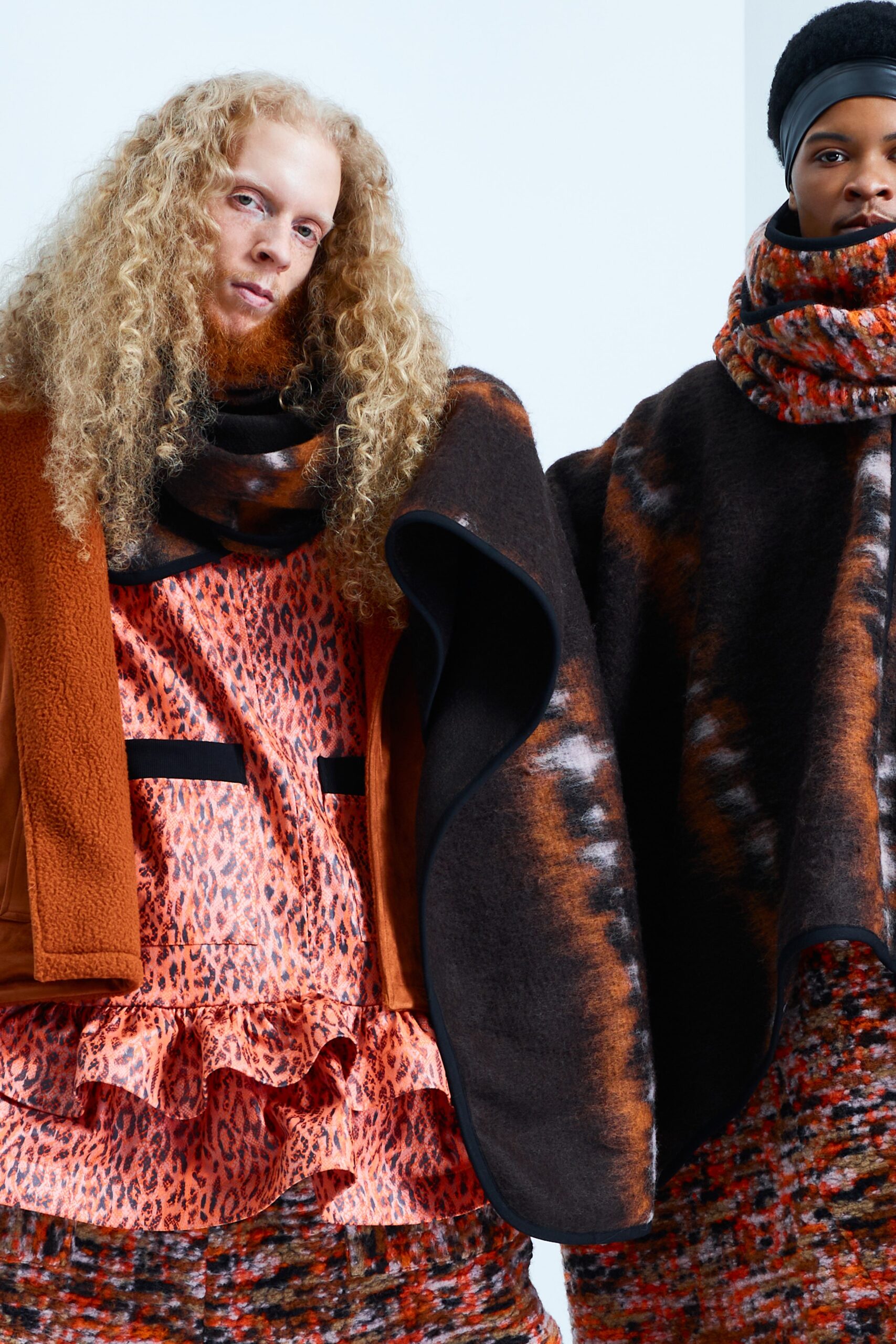 This relaxed dress features a playful ruffled hem and a striking animal-print pattern, creating a dynamic visual appeal. Layered under a cozy brown coat, the ensemble balances warmth with a bold style statement.