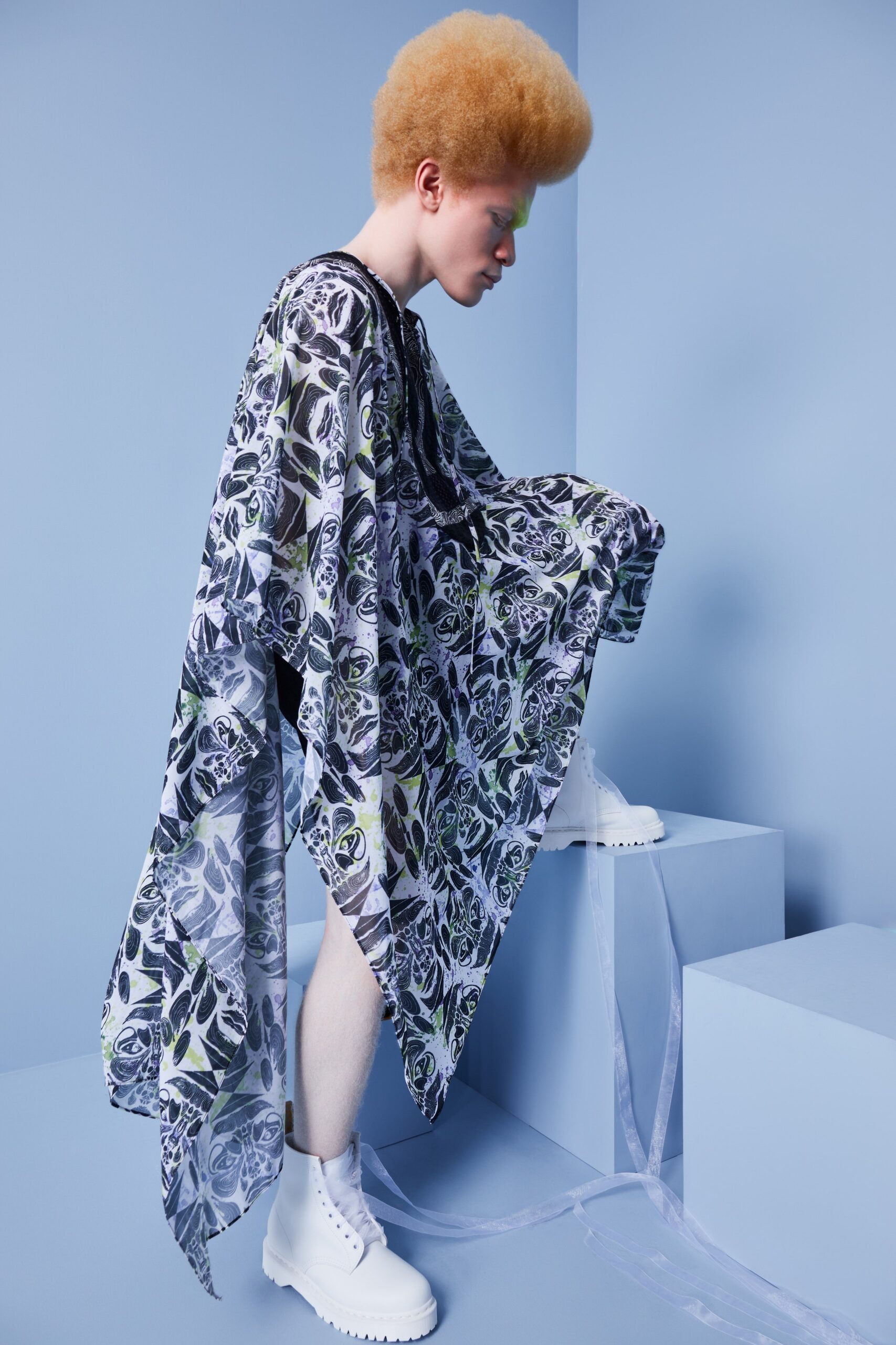 This oversized poncho features a striking floral print in black and white, creating a dramatic visual impact. The lightweight chiffon fabric flows gracefully, enhancing movement and adding an ethereal quality to the silhouette.