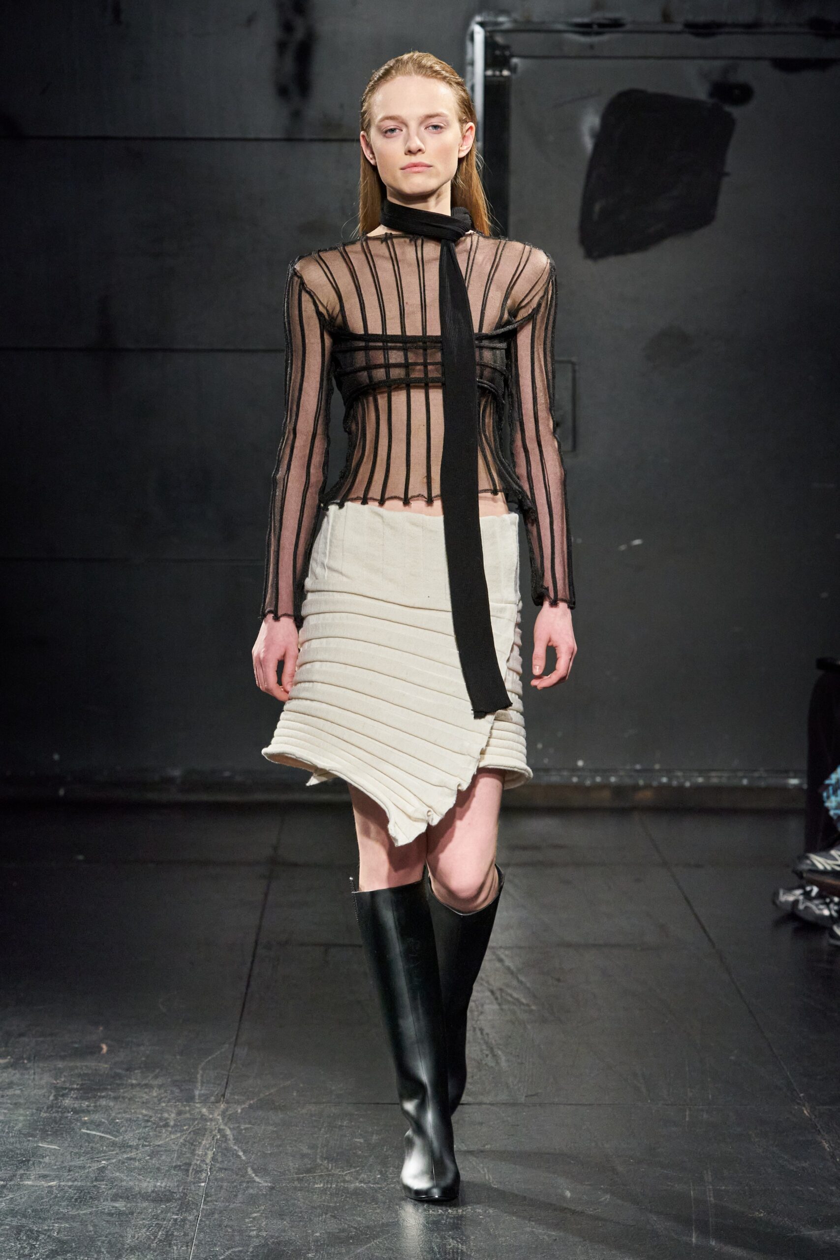 A fitted black silk long-sleeve top with a V-neck and an asymmetric white pleated skirt.
