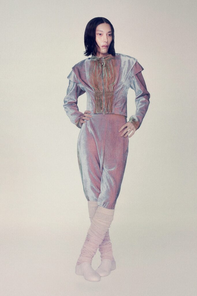 A fitted gray velvet jumpsuit with long sleeves and an asymmetric design detail.