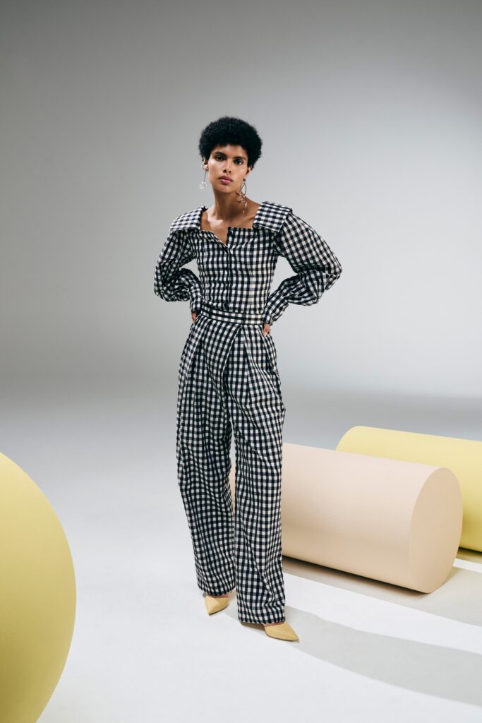 A fitted black and white checked jumpsuit with a collared neckline and long sleeves.