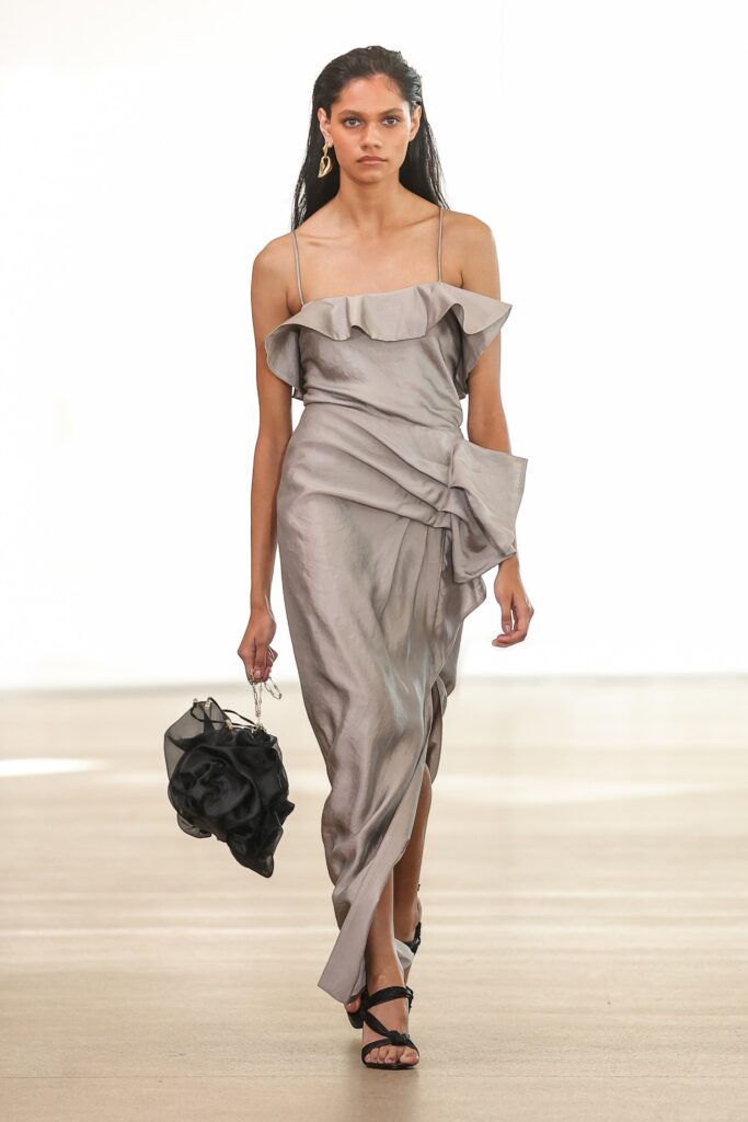 A fitted gray silk dress with an off-shoulder design and ruffled detailing.