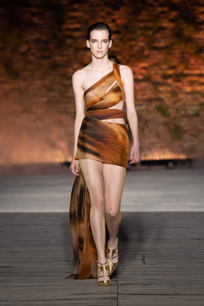 A fitted brown silk dress with an asymmetric design and tiered detailing.