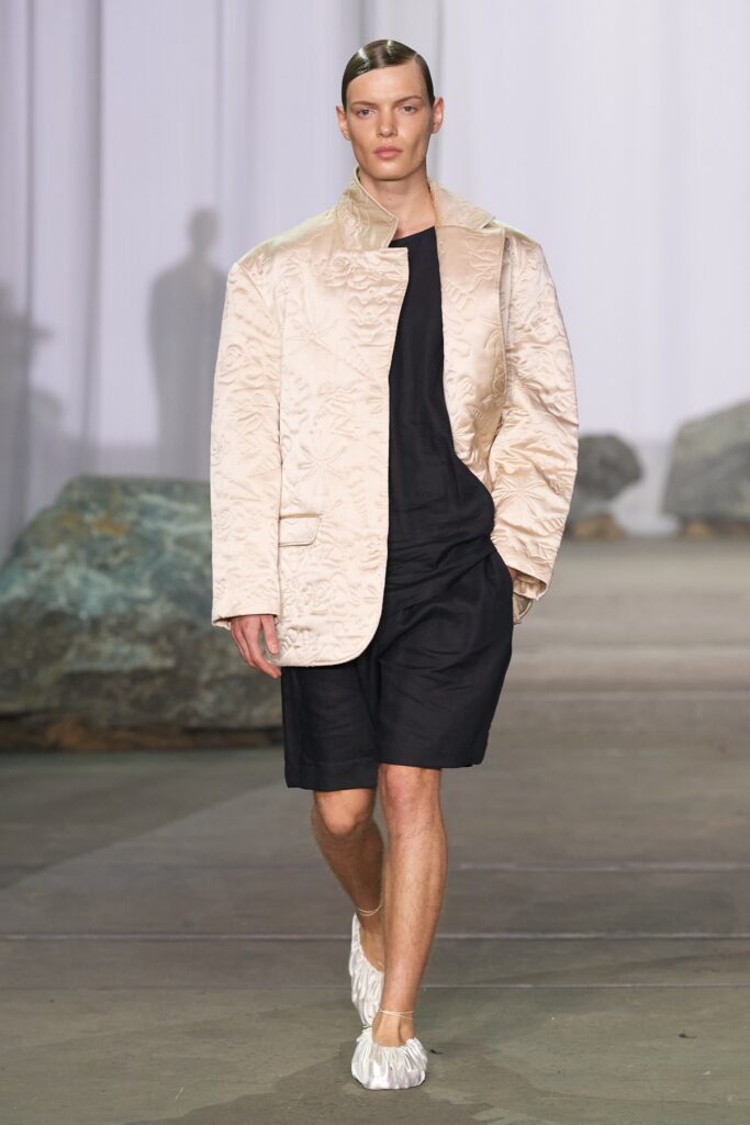 A relaxed-fit beige embroidered jacket paired with black shorts for a contemporary look.