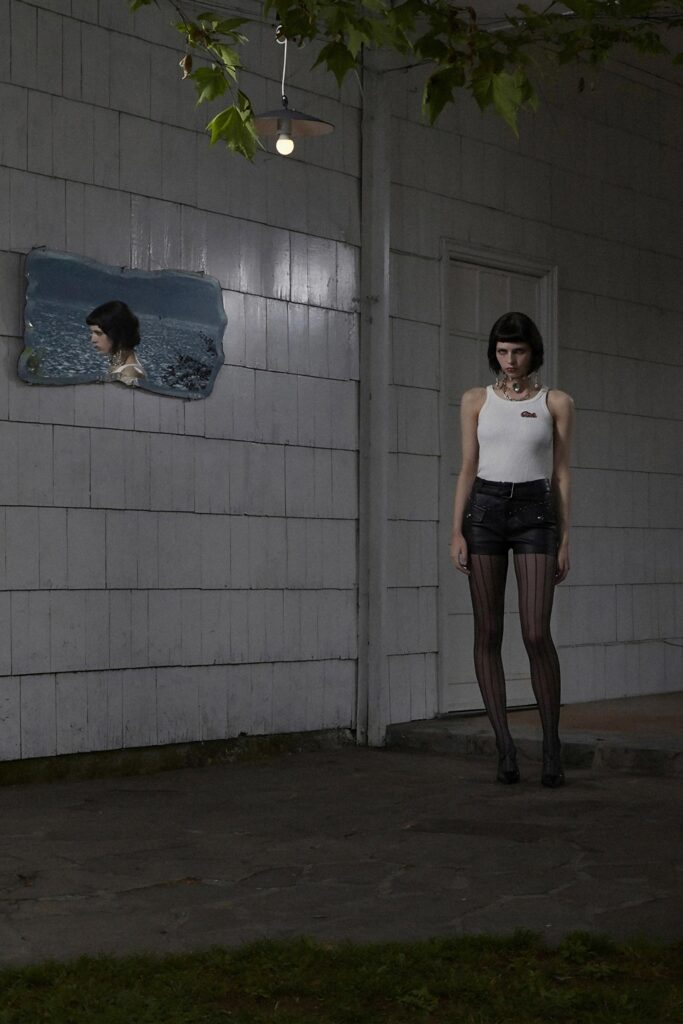 A fitted white sleeveless top paired with black denim shorts featuring a striped design.