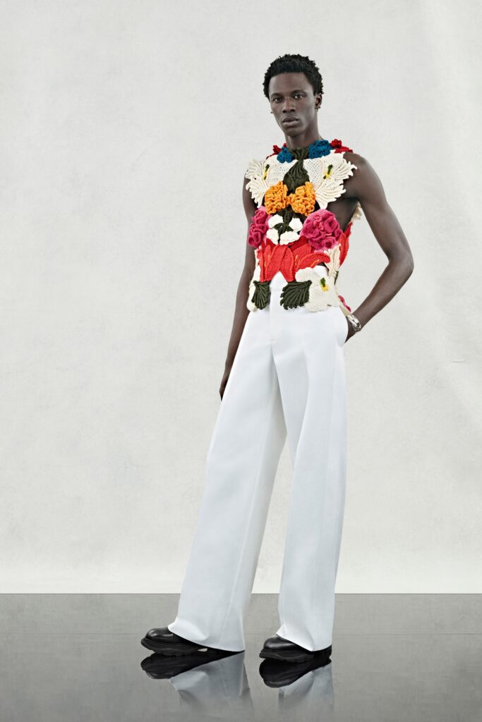 A fitted white pants outfit paired with a colorful floral sleeveless top.