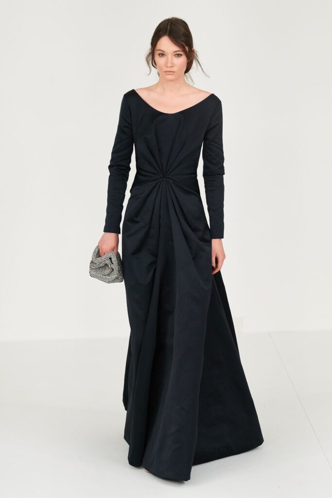 A fitted black silk dress with long sleeves, a V-neckline, and pleated design detail.