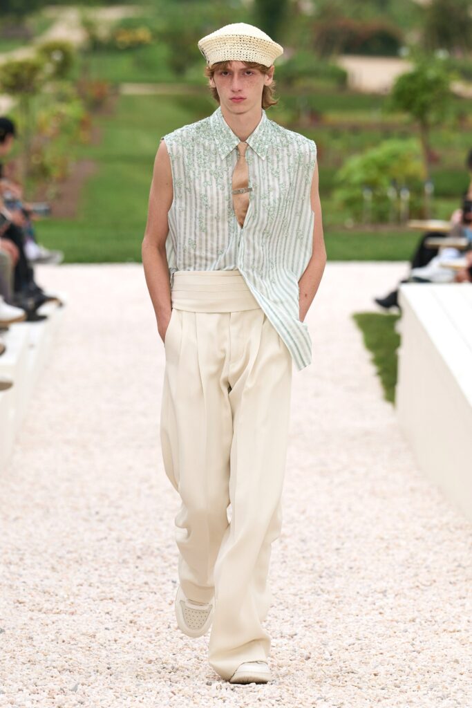 A relaxed white striped sleeveless shirt paired with pleated pants, creating a stylish ensemble.
