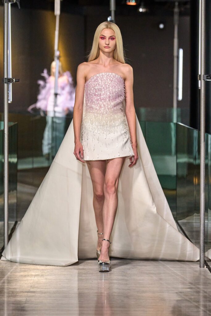 A fitted strapless dress in pink and white with an asymmetric silhouette.