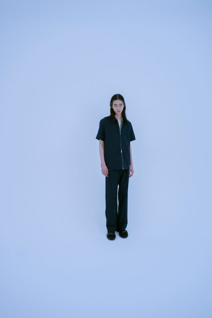 A relaxed black shirt with short sleeves and a collared neckline paired with straight-leg pants.