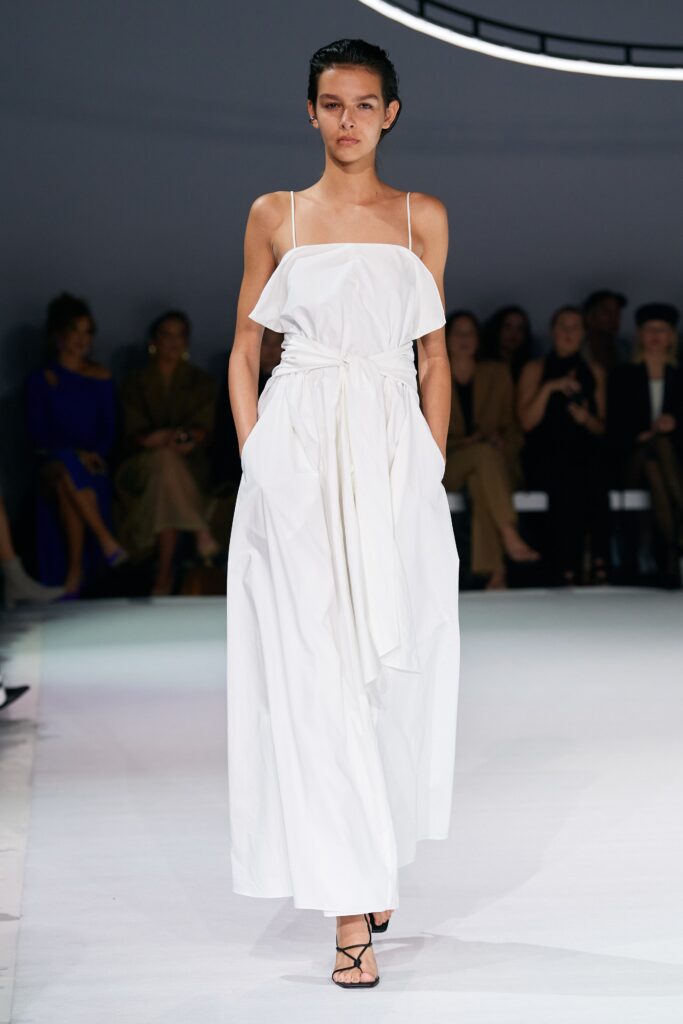 A relaxed white sleeveless dress with a V-neckline and tiered design.