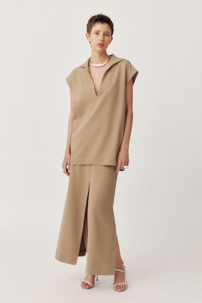 A relaxed beige sleeveless top with a V-neck and a matching skirt featuring a slit.