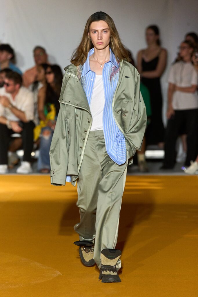 A relaxed green jacket with a collared neckline paired with blue pants.