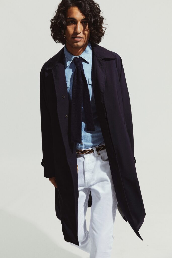 A relaxed black coat layered over a collared blue shirt with button details.