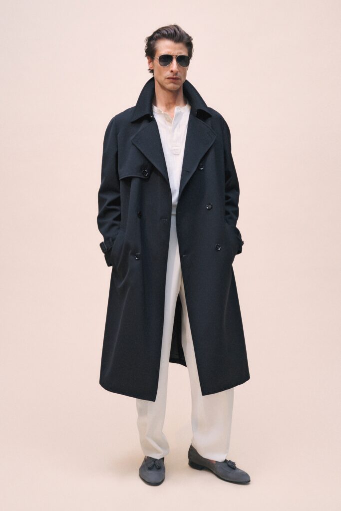 A relaxed black coat paired with white pants, featuring a collared design and buttoned details.