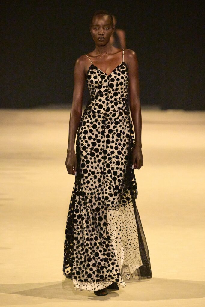A fitted sleeveless dress featuring a V-neckline and tiered design with polka-dot pattern.