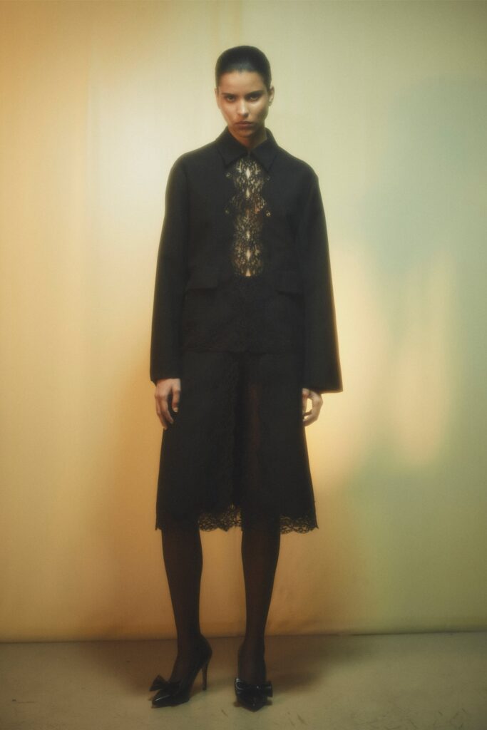 A fitted black lace dress layered with a matching coat featuring a collared neckline.