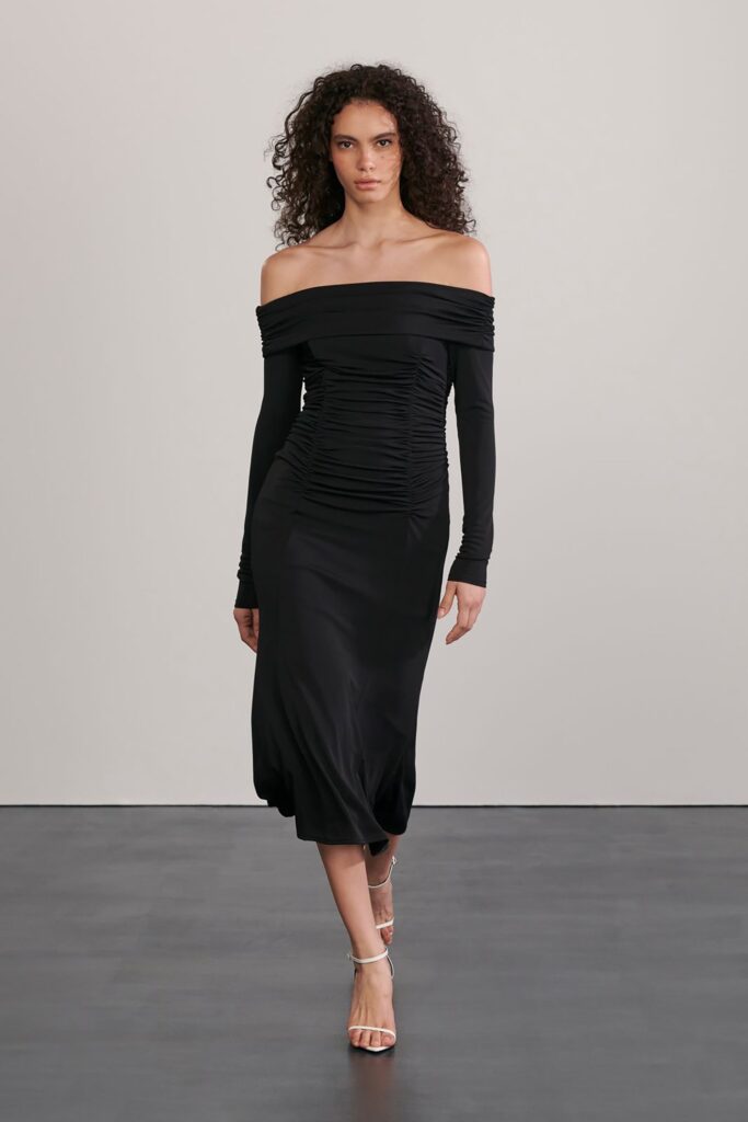 A fitted black silk dress with long sleeves and an off-shoulder design featuring ruched detailing.