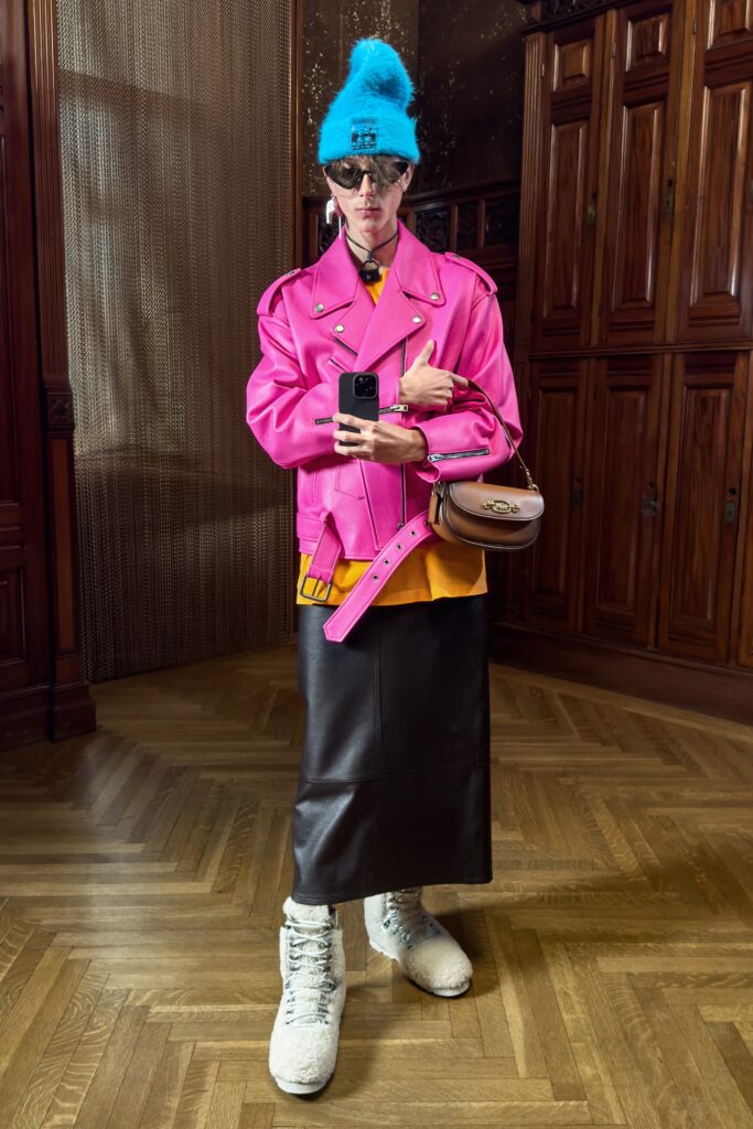 A fitted pink leather jacket with a long-sleeve design paired with a black asymmetric skirt.