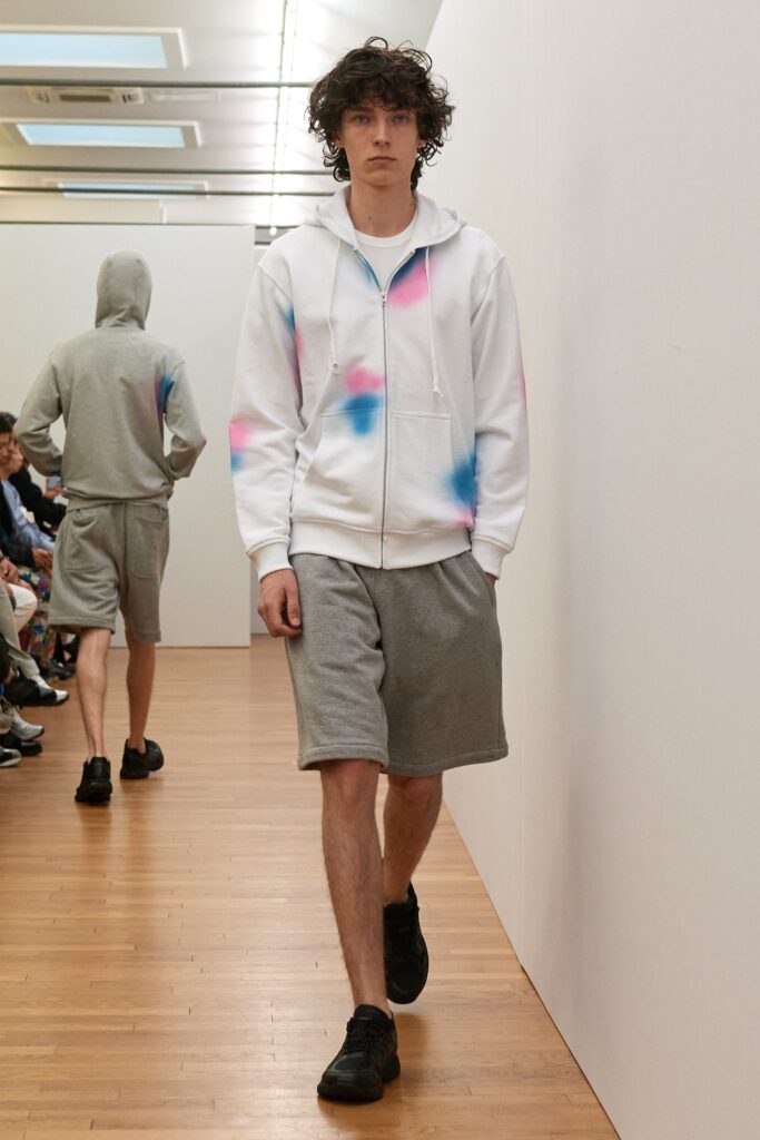 A relaxed-fit white hoodie with color-blocked details paired with gray shorts.