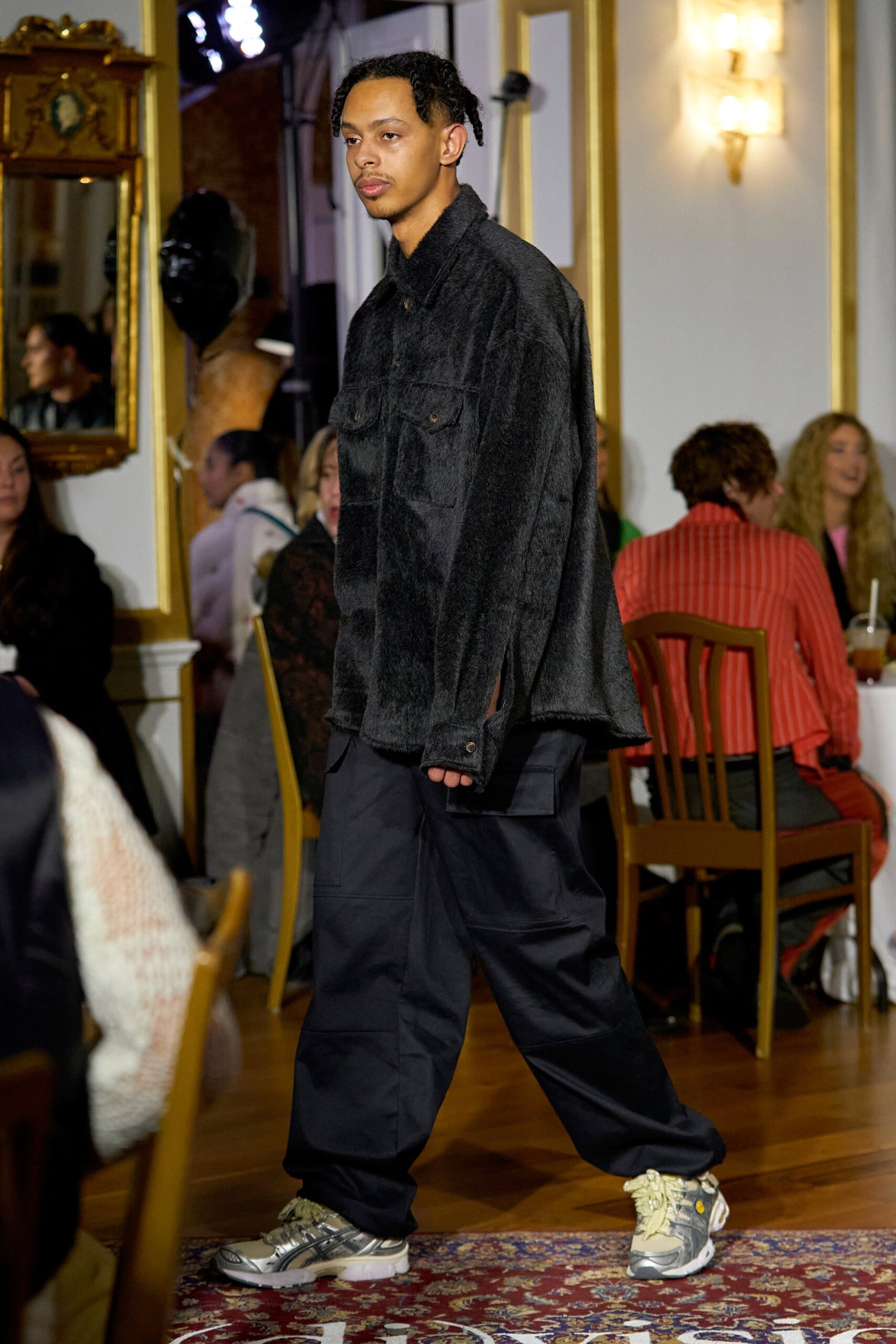 A relaxed black faux-fur jacket paired with black pants, featuring a zippered detail.