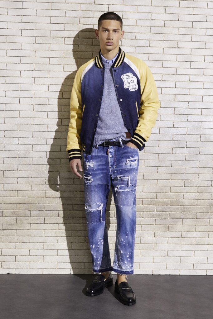 A relaxed fit blue denim jacket with yellow accents paired with distressed denim pants.