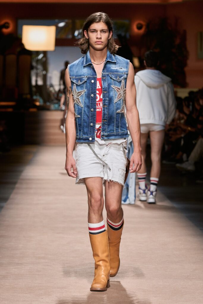 A fitted blue denim sleeveless vest paired with distressed white shorts for a casual look.