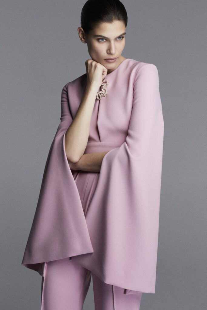 A fitted pink silk cape with long sleeves and an asymmetric design.