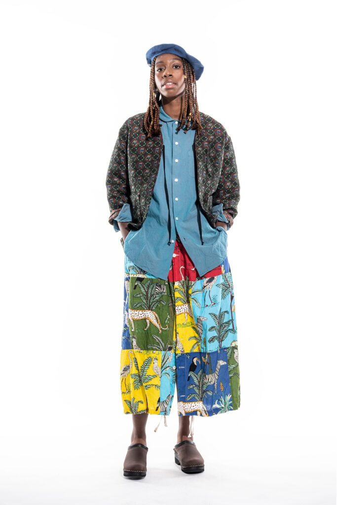 A relaxed fit jacket over a collared shirt paired with a printed skirt in vibrant colors.