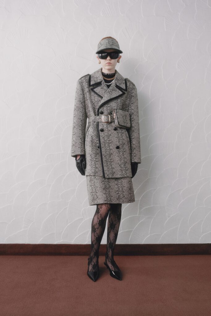 A fitted gray printed coat dress with long sleeves and a belted waist.
