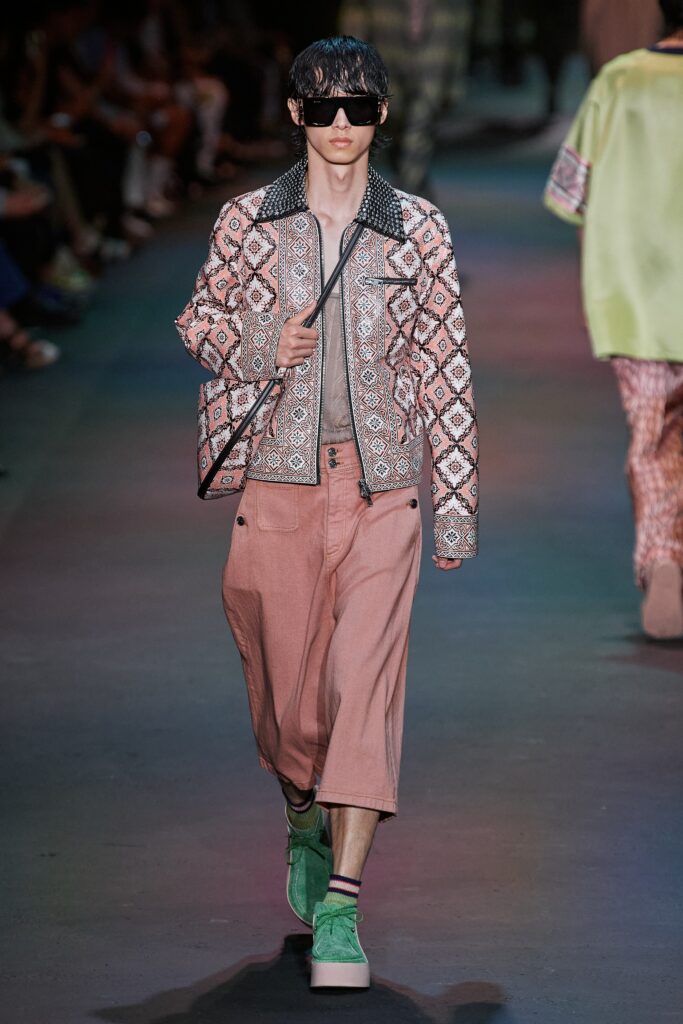 A relaxed-fit embroidered pink cotton jacket paired with beige wide-leg pants.
