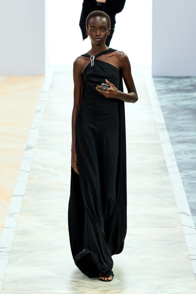 A relaxed black silk sleeveless dress with a high neckline and asymmetric design.