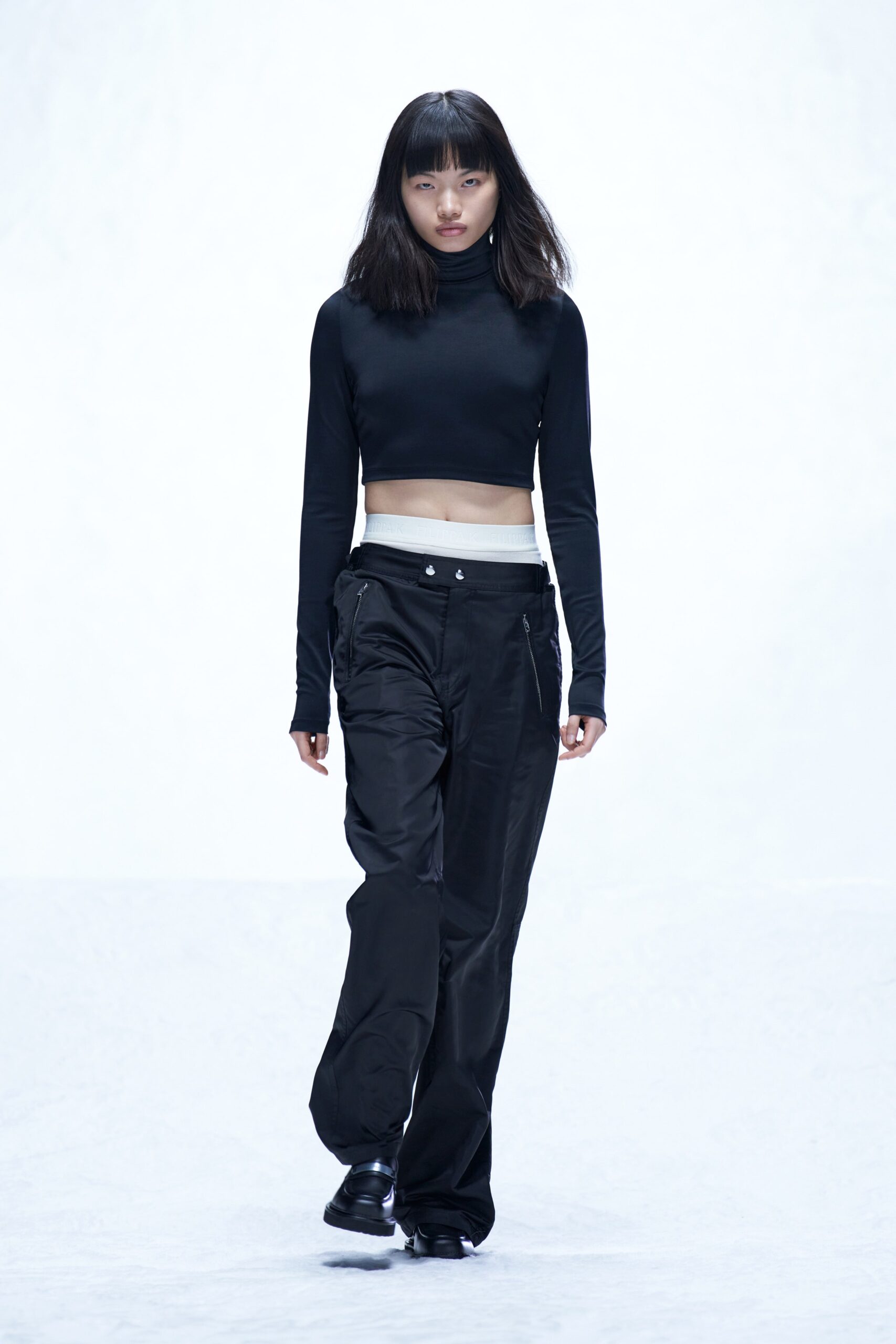 A fitted black long-sleeve top with a high neck paired with straight-leg black pants.