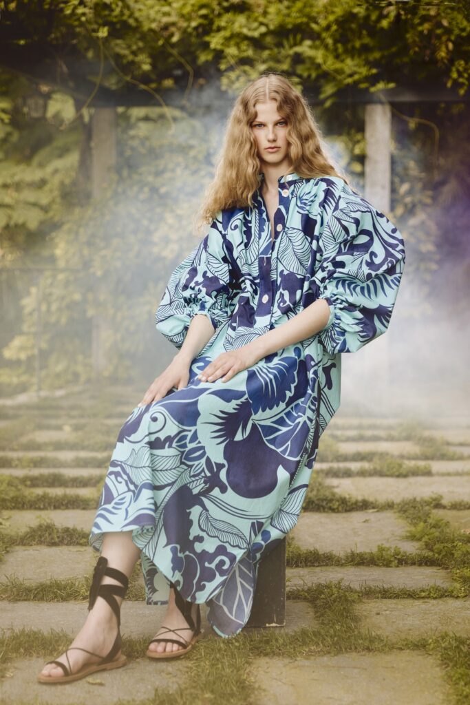 A relaxed blue dress with long sleeves, a collared neckline, and a vibrant printed design.