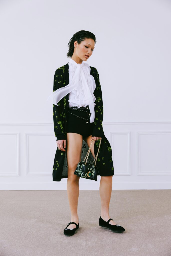 A fitted black embroidered cardigan paired with white shorts for a chic look.