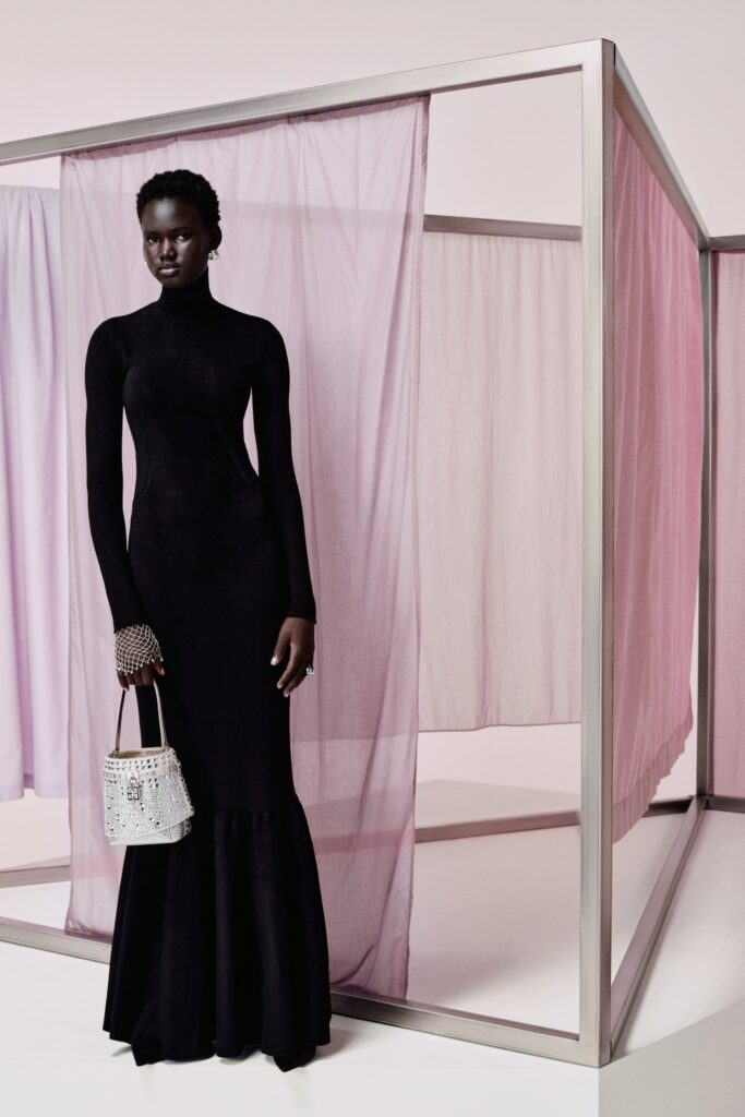 A fitted black velvet dress with long sleeves and a high neckline, featuring a flared silhouette.