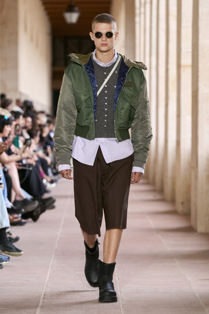 A relaxed green jacket with a collared long-sleeve shirt and brown shorts, featuring a layered look.