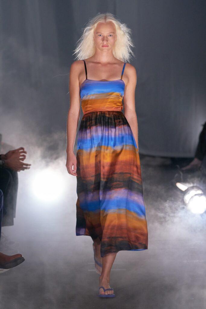 A relaxed sleeveless dress made of silk featuring a V-neckline and tiered design in blue, orange, and brown hues.