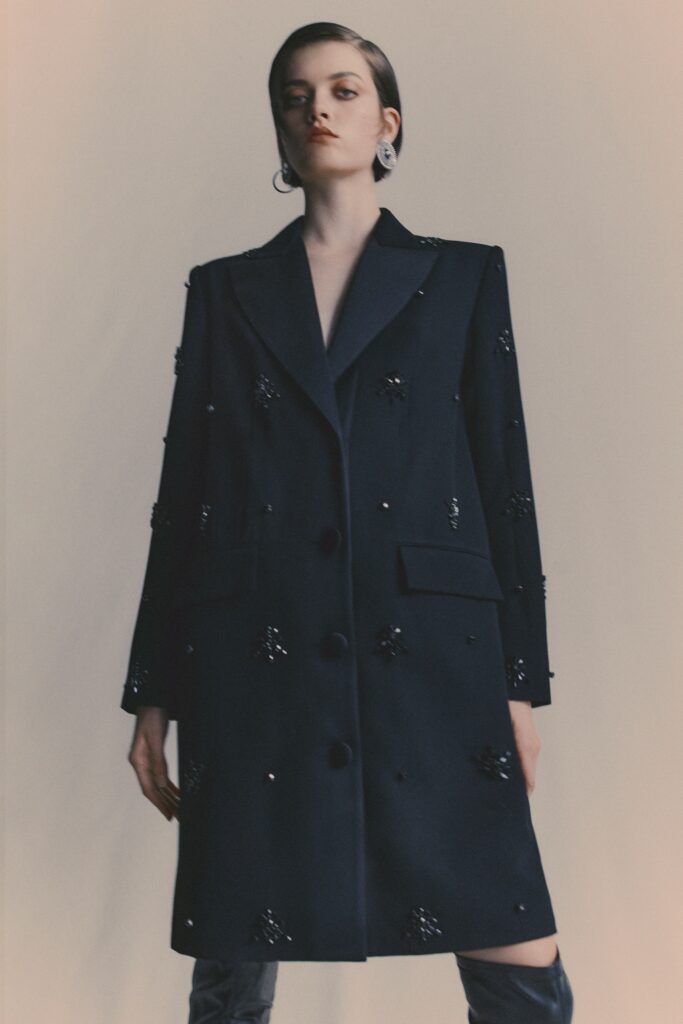 A structured navy wool coat with long sleeves and embroidered detailing.