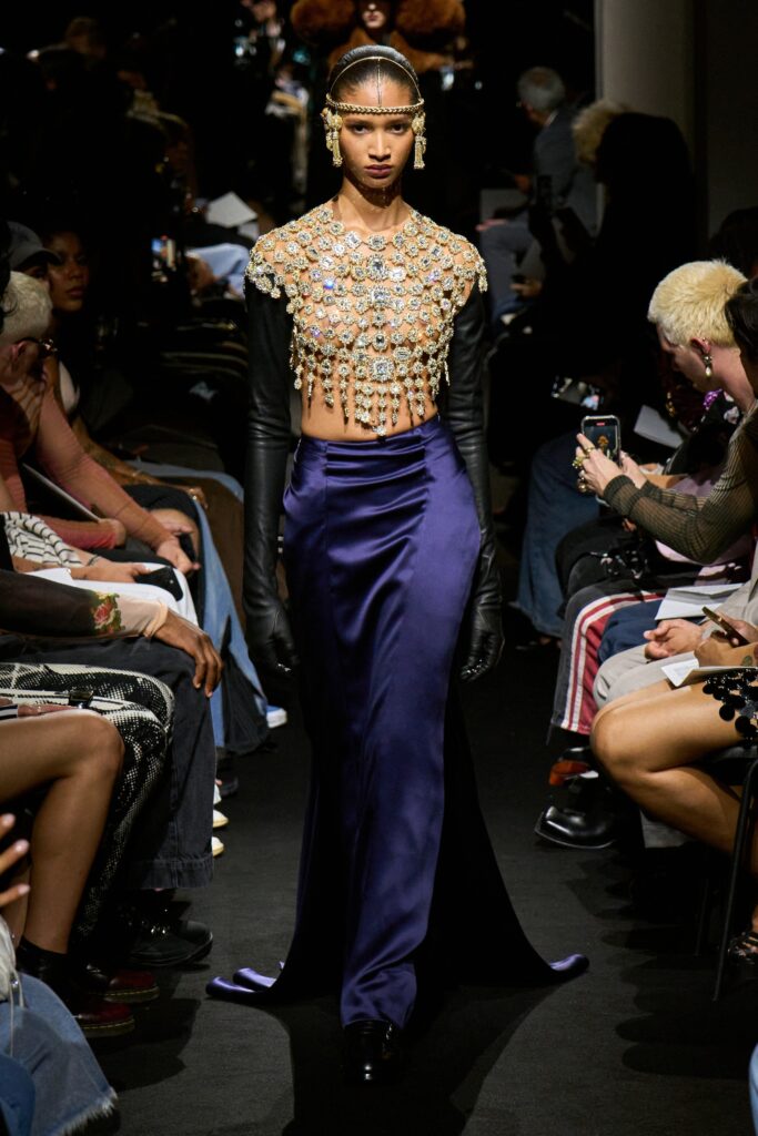 A fitted purple silk dress with long sleeves, high neckline, and a stylish slit.