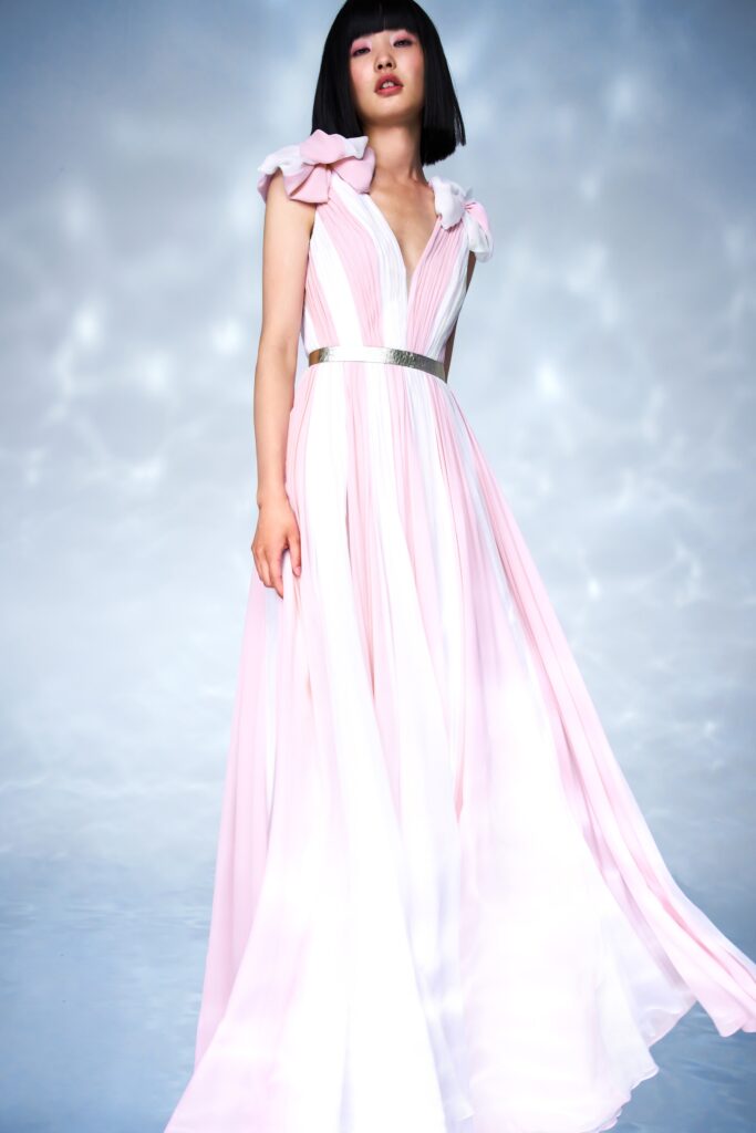A fitted pink silk dress with a V-neckline and pleated design details.