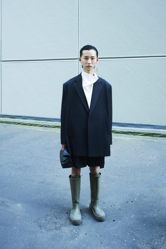 An oversized black jacket paired with shorts, featuring a collared design and asymmetric details.