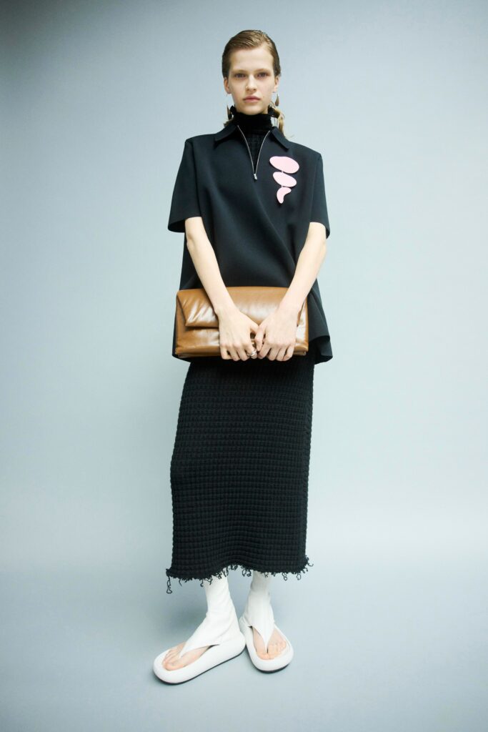 A relaxed black top with short sleeves and a collared design paired with an asymmetric black skirt.