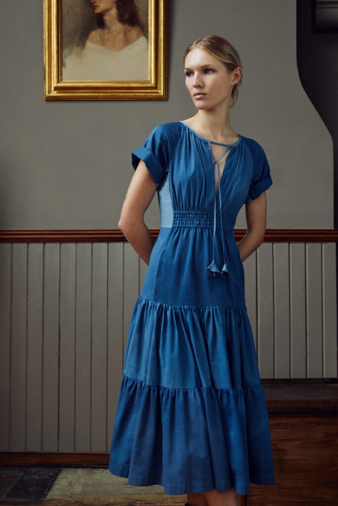 A relaxed blue cotton dress with short sleeves, a V-neckline, and a tiered design.
