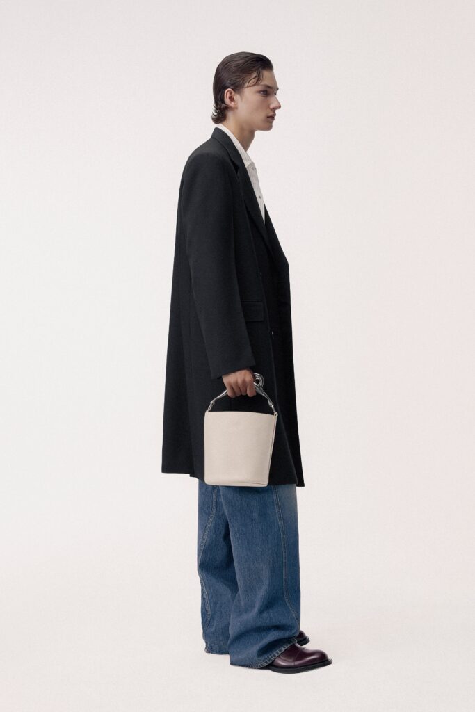 A relaxed black coat paired with straight-leg blue denim pants.