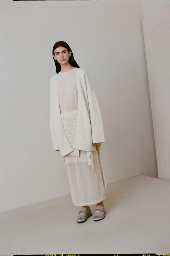 A relaxed white dress layered with a long-sleeve coat, featuring a collared design.