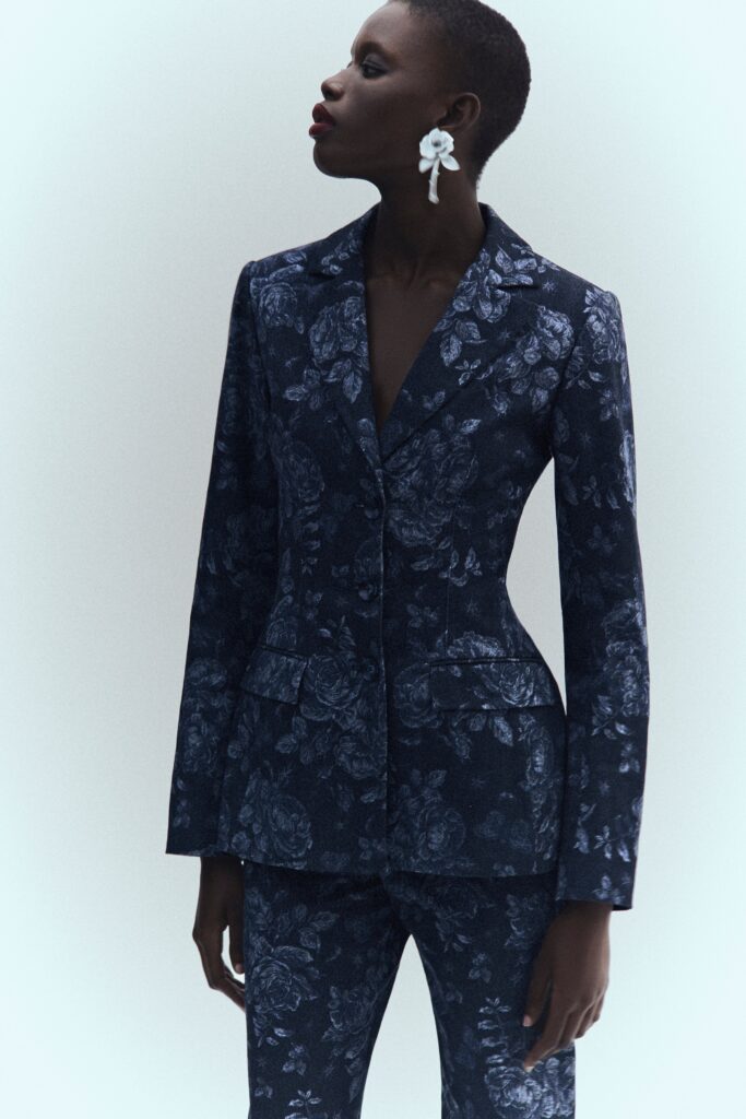A fitted blue floral blazer with long sleeves and a collared design, paired with matching pants.