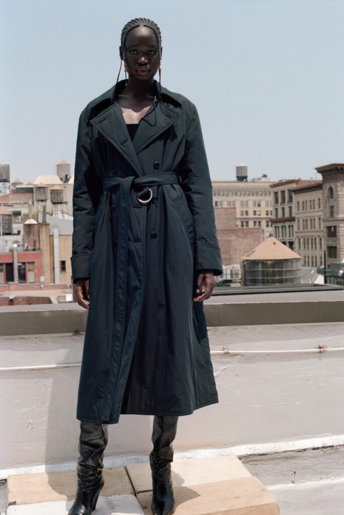 A relaxed black coat with long sleeves, a collared neckline, and a belted detail.